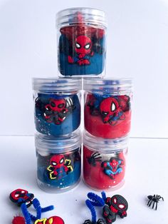 four plastic containers filled with spiderman candles and magnets on top of each other