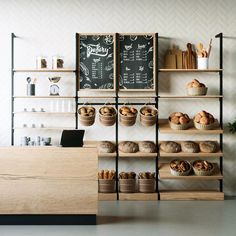 the bakery is stocked with breads and muffins on shelves, along with chalkboard menu boards