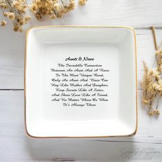 a white and gold plate with the names of people on it next to dried flowers