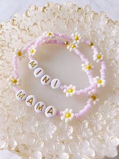 two personalized bracelets sitting on top of a white plate with yellow and pink beads