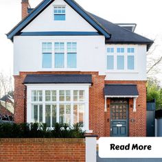 a large white brick house with a black roof and windows that read read more on the front door