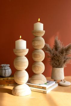 three candles sitting on top of a table next to some books and a potted plant