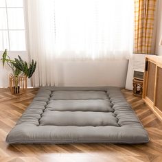 a futon mattress is sitting on the floor in front of a window