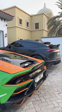 two sports cars parked next to each other in front of a building with palm trees