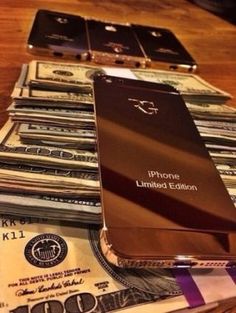 a stack of money sitting on top of a wooden table next to a cell phone