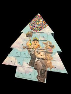 a cardboard christmas tree with an image of two men and a dog on it, surrounded by sprinkles