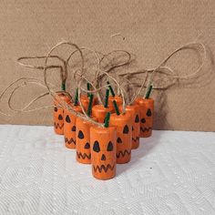 small orange pumpkins with faces painted on them are arranged in a row and tied to twine