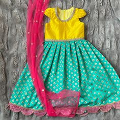 Anarkali gown for babies, toddlers, and girls This yellow raw silk and teal brocade anarkali gown features god trim at neck and waist and standout pink and gold scallop trim at the hem of the dress. Unique racer back with zipper closure makes that dress easy to get in and out of. This dress is fully lined in a soft cotton so there is nothing itchy, scratchy, or uncomfortable against your child's skin. Contrasting pink sequin net dupatta adds extra color and glamor to this outfit! Outfits are ful Transitional Yellow Bollywood Dress, Yellow Gown With Pallu For Eid, Yellow Traditional Drape Dress For Eid, Yellow Self Design Dress For Wedding, Traditional Drape Yellow Dress For Eid, Yellow Lehenga For Party And Transitional Seasons, Yellow Lehenga For Transitional Party Season, Yellow Gown With Pallu For Festive Occasions, Yellow Lehenga For Transitional Party