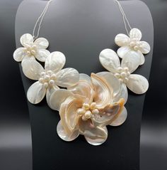 a necklace with flowers and pearls is on display in front of a mannequin