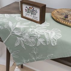 the table is covered with a green and white flowered tablecloth next to a wooden tray