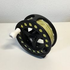 a spool of yellow and black fishing line on a white counter top with a wall in the background