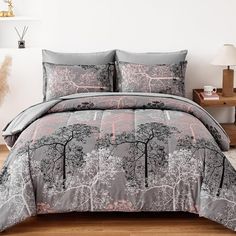 a bed covered in grey and pink comforter with trees printed on the coverlet