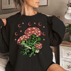 The perfect comfy and cozy mushroom crewneck sweatshirt is the ideal gift for any nature or mycophile lover, for the ideal  Christmas present for mom, family members, best friend, or any occasion to put a smile on their faces! Item Details: Gildan 18000 8.0 oz., pre-shrunk 50% cotton, 50% polyester Classic fit with no center crease Air-jet spun yarn with a soft feel and reduced pilling 1x1 athletic rib knit collar, cuffs and waistband, with spandex Tear away label Care Instructions: Machine wash Casual Fall Sweatshirt With Mushroom Print, Casual Mushroom Print Sweatshirt For Fall, Fall Mushroom Print Crew Neck Sweatshirt, Casual Crew Neck Sweatshirt With Mushroom Print, Casual Long Sleeve Top With Mushroom Design, Black Crew Neck Top With Mushroom Print, Cotton Crew Neck Sweatshirt With Mushroom Print, Mushroom Print Tops For Fall Streetwear, Fall Mushroom Design Crew Neck T-shirt