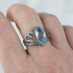 Sterling Silver Filigree Art Woman Cocktail Ring with Dazzling Blue Topaz Gemstone Artfully Abstract and Eye-Catching Our sterling silver filigree cocktail ring featuring Blue Topaz gemstone is an artistic style standout. Skilled artisans expertly shape the asymmetrical band into an avant-garde, dimensional form that boldly bucks convention. Heirloom Ring Crafted to Withstand Time The dazzling Blue Topaz takes center stage in this substantial ring, set securely within the ornate textured metalwo Heirloom Ring, Heirloom Rings, Angel Design, Silver Cocktail, Heirloom Gifts, Blue Topaz Gemstone, Artistic Style, Sterling Silver Filigree, Ring Crafts