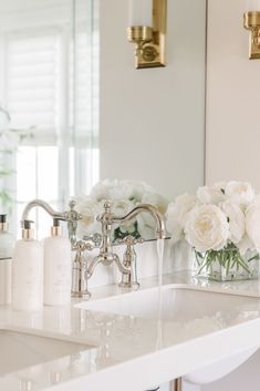 a white bathroom sink sitting under a large mirror next to a wall mounted faucet