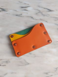 an orange and yellow wallet sitting on top of a marble counter