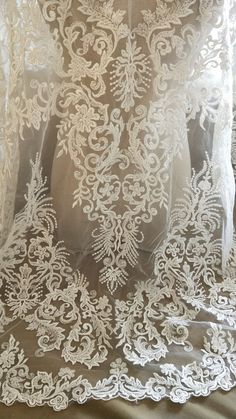 the back of a wedding dress with white lace on it