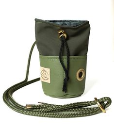 a green and black purse sitting on top of a white table next to a cord