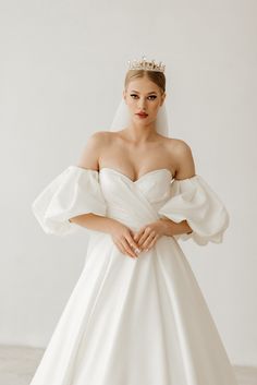 a woman in a white wedding dress with a tiara on her head is posing for the camera