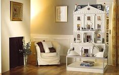 a doll house sitting on top of a white shelf in a living room next to a chair