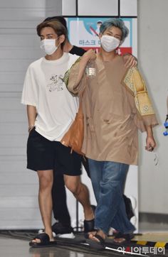 two people wearing face masks while walking through an airport