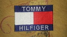 the tommy hilfiger logo is shown in blue, red and white on a gold background