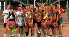 a group of young men standing next to each other on a basketball court with their arms in the air