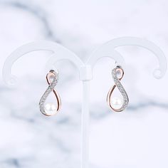 Elegant and stunning, this pair of earrings makes a perfect gift for loved one or yourself. Crafted in two tone sterling silver, the earrings are shaped in asymmetric infinity design. Infinity is one of the most popular motifs in jewelry design. It's stands for eternal love. With the shimmering stones and beautiful white pearls, the earrings will be an eye-catcher everywhere. Just add this masterpiece to your jewelry box.Carat Weight: 2.286 ctStone Size: 1.1,0.9,5 mmStone Type: Jeulia® StoneNumb Elegant Infinity Earrings For Formal Occasions, Elegant Infinity White Gold Earrings, Elegant White Gold Infinity Earrings, Infinity Earrings For Formal Occasions, Silver Infinity Earrings For Formal Occasions, Silver Infinity Earrings For Formal Events, Elegant Silver Infinity Shaped Earrings, Elegant Silver Infinity Earrings, Elegant Infinity Earrings For Anniversary