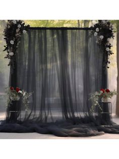 an image of a wedding ceremony setting with flowers on the stage and black sheer curtains