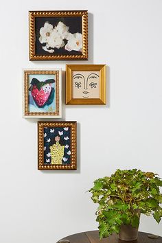 a potted plant sitting on top of a wooden table next to three framed pictures