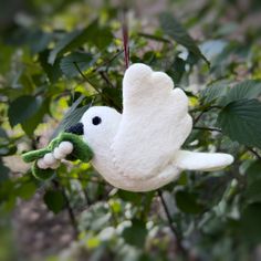 a white stuffed bird hanging from a tree