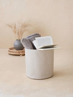 an open book sitting on top of a table next to a vase with a plant in it