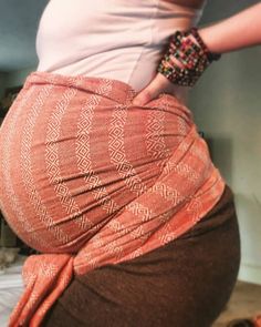 a pregnant woman is standing with her hands on her hips and wearing an orange skirt