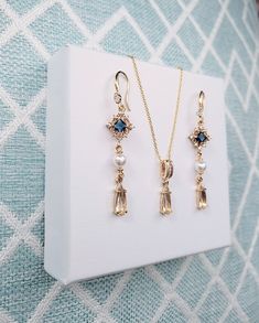 High quality champagne gold plated Gatsby style earrings and necklace set with navy blue cubic zirconia stones and faux pearls. The top navy blue rhinestone has beautiful intricate filigree work around it.  The chain is 1mm thick and 46cm long. It is easily adjustable to make it shorter to your desired length simply by pulling on the chain through the round gold bead. It also has 2 removal options - using the clasp or pulling the chain out of the round gold bead as shown in the pictures. There are 2 jewelry box options: Box A: regular jewelry cardboard box with a textured diamond pattern on the outside (comes in white, black or red) Box B: Velvet earring and necklace box (comes in green, red and grey) You can also add a mini gift bag as show in the pics: comes with green, red or grey satin Elegant Gold Drop Jewelry Set, Art Deco Jewelry Set With Matching Earrings For Gifts, Art Deco Jewelry With Matching Earrings For Gifts, Art Deco Jewelry Set With Matching Earrings As Gift, Art Deco Jewelry With Matching Earrings As Gift, Vintage Cubic Zirconia Dangle Jewelry, Victorian Dangle Jewelry With Matching Earrings, Victorian Jewelry With Matching Dangle Earrings, Art Deco Yellow Gold Jewelry For Jewelry Making