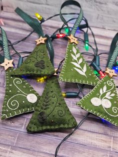 four green christmas tree ornaments with lights on the top and one is hanging from a string