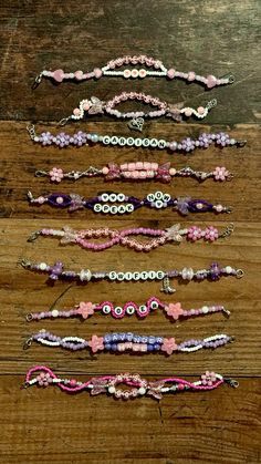 several bracelets are lined up on a wooden surface, one is pink and the other is purple