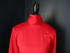 "Vintage red professional blouse from JH Collectibles. Long sleeves with thick button cuff at wrist, and buttons up back of high neck collar. Waist is tailored and defined. Padded shoulders. 100% Polyester Size 8. 20\" underarm to underarm 24\" sleeve 25.5\" length." Fitted Solid Tops With Stand Collar, Fitted Solid Color Top With Stand Collar, Formal Stretch Blouse, Stretch Blouse For Formal Occasions, Solid Stretch Blouse For Formal Wear, Fitted High Neck Blouse For Fall, Formal Stretch Winter Tops, Fitted Stand Collar Top For Office, Fitted High Neck Blouse