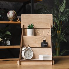 a wooden shelf with an alarm clock, plant and other items on top of it