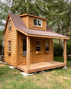 a small wooden house with a porch and covered in shingles