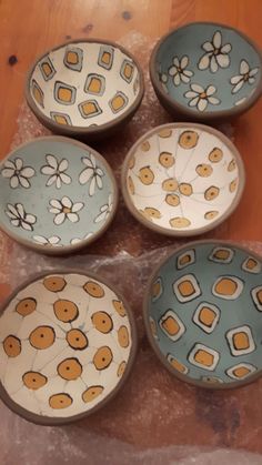 four bowls with flowers painted on them sitting on a table