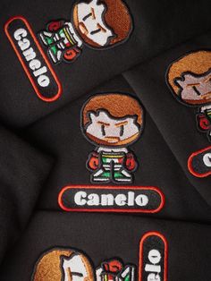 four black sweatshirts with orange and white patches on the front, one has an image of a cartoon character