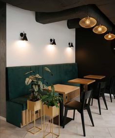 a restaurant with green velvet booths and wooden tables, black chairs, and hanging lights