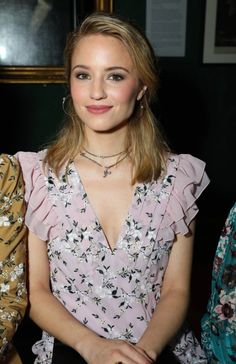 a beautiful young woman sitting in front of a mirror wearing a pink dress and smiling at the camera