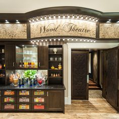 the wood theatre bar has many bottles and glasses on it's display shelves, along with an assortment of drinks