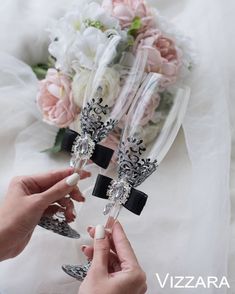 two brides toasting champagne flutes with black and white decorations on the stems in front of their bouquet