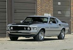 an old muscle car parked in front of a garage