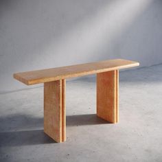 a wooden bench sitting on top of a cement floor next to a white wall in an empty room