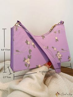 a woman is holding a purple handbag with flowers on it and measurements for the strap