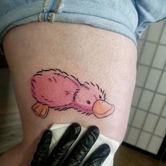 a woman's thigh with a pink hedgehog tattoo on her left leg and black gloves