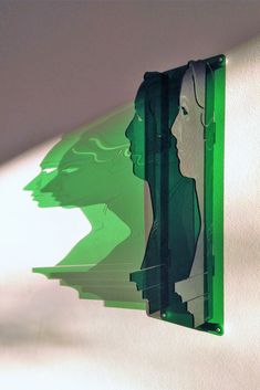 an image of a woman's profile on a green glass block hanging from the wall